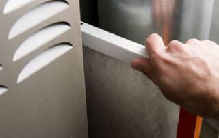 A man removes a dirty air filter from an HVAC system