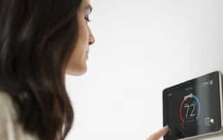 A woman adjusts a thermostat