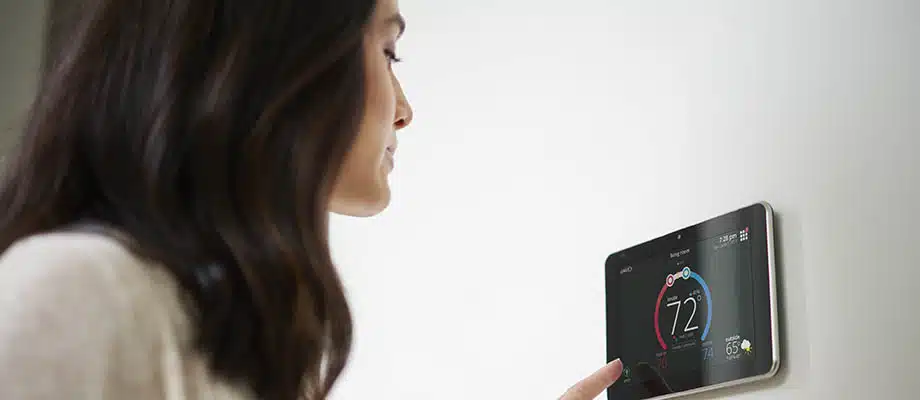 A woman adjusts a thermostat