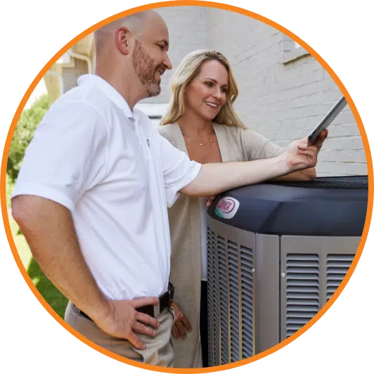 A HVAC technician speaks with a homeowner near an air conditioner.