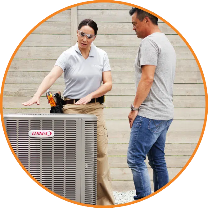 A HVAC technician talks to a homeowner near an air conditioner.