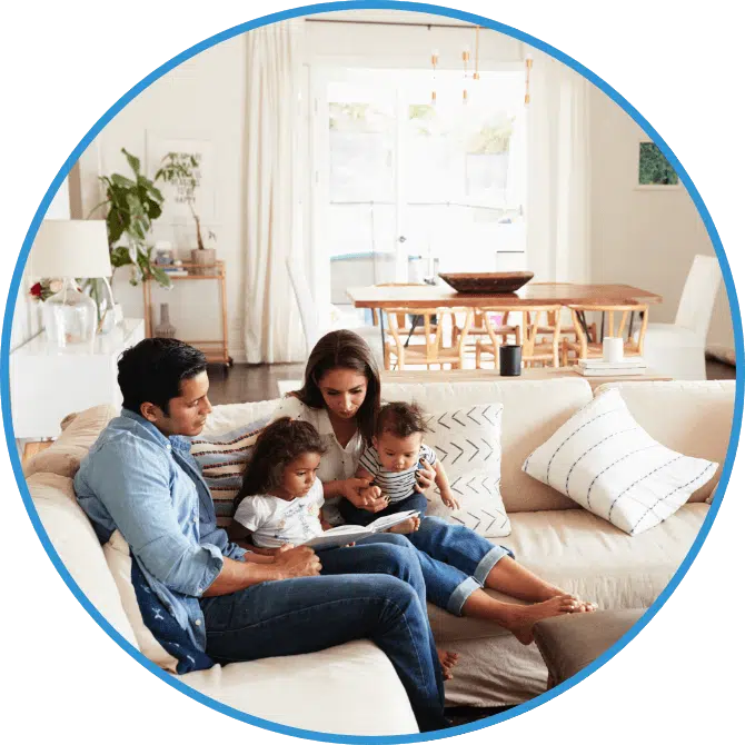 A family reads a book together while sitting on a couch.