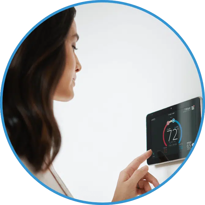 A woman adjusts a thermostat